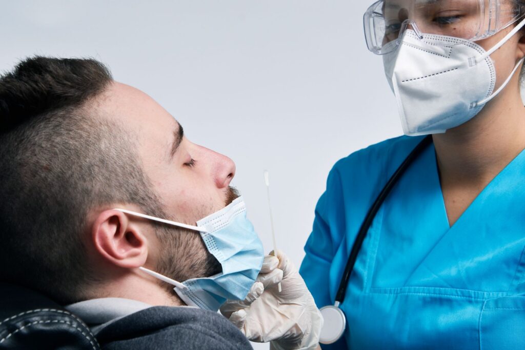 Medical professional performing COVID-19 swab test on a patient in a clinical setting.