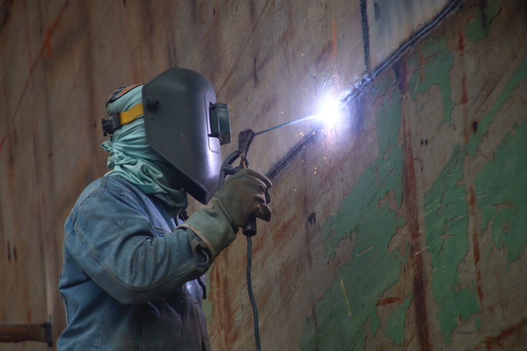 A welder works in a Keraniganj shipyard, highlighting industrial labor's skilled techniques.
