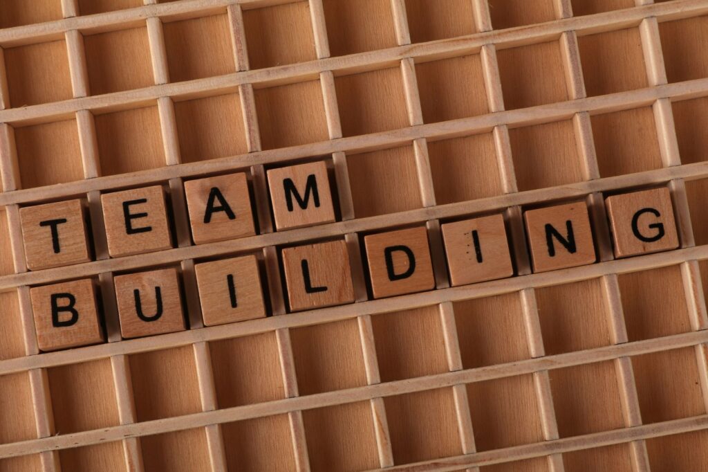 Scrabble letters spelling 'TEAM BUILDING' on a wooden board symbolize teamwork and collaboration.