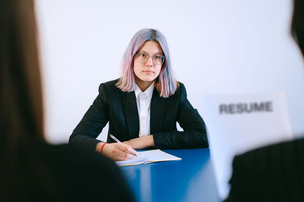 A young woman in a suit during a job interview, writing notes.