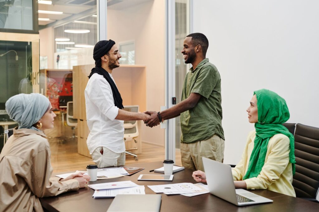 A diverse team meeting in a modern office with people shaking hands, symbolizing teamwork and collaboration.