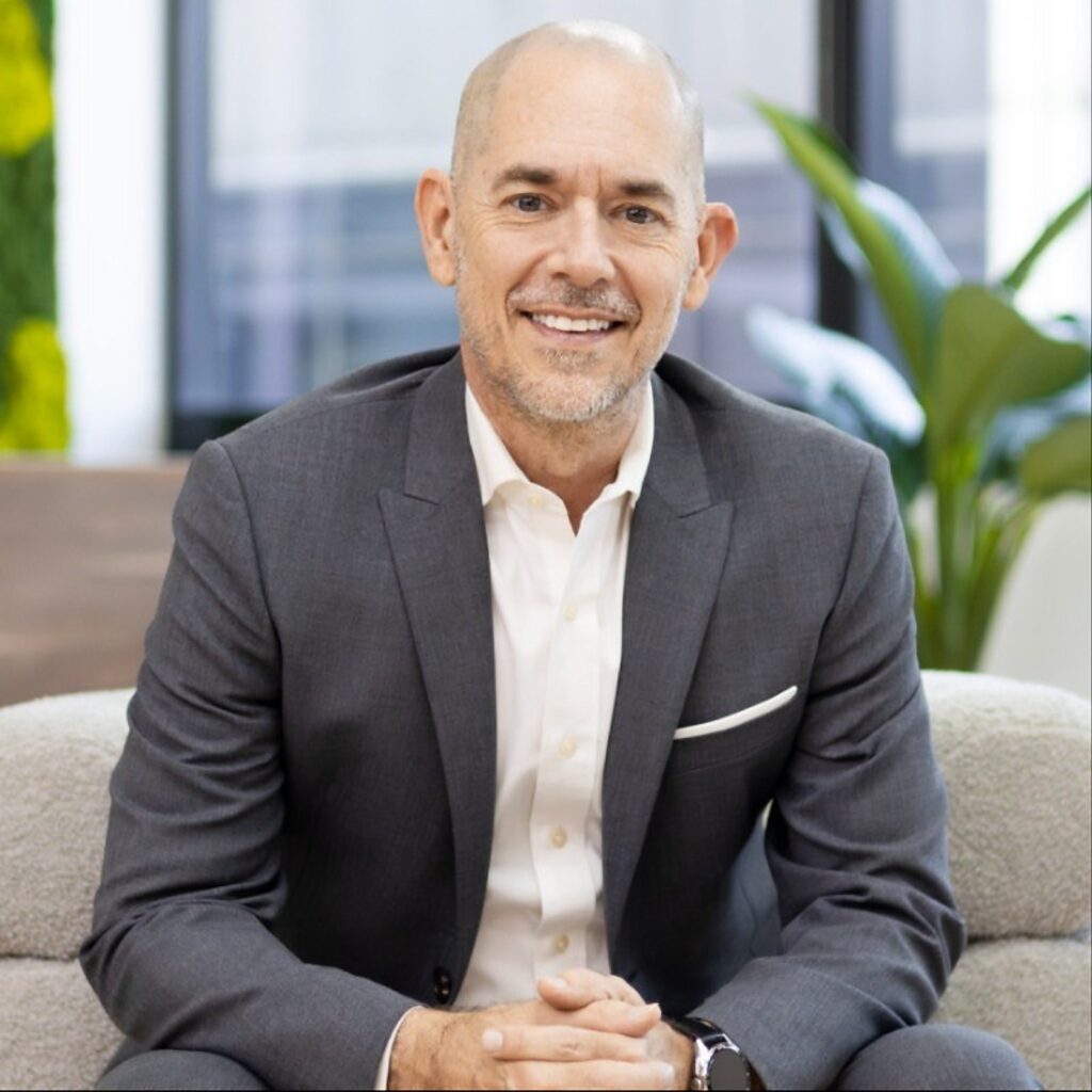 Andy Schachtel, founder and CEO of Sourcefit, seated in a grey suit with his hands clasped