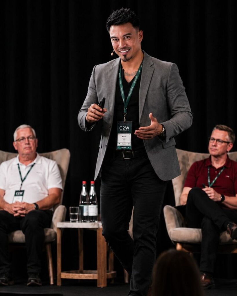 Marco Perrott, CEO of LYRIQ, smiling as he speaks on stage in a grey blazer